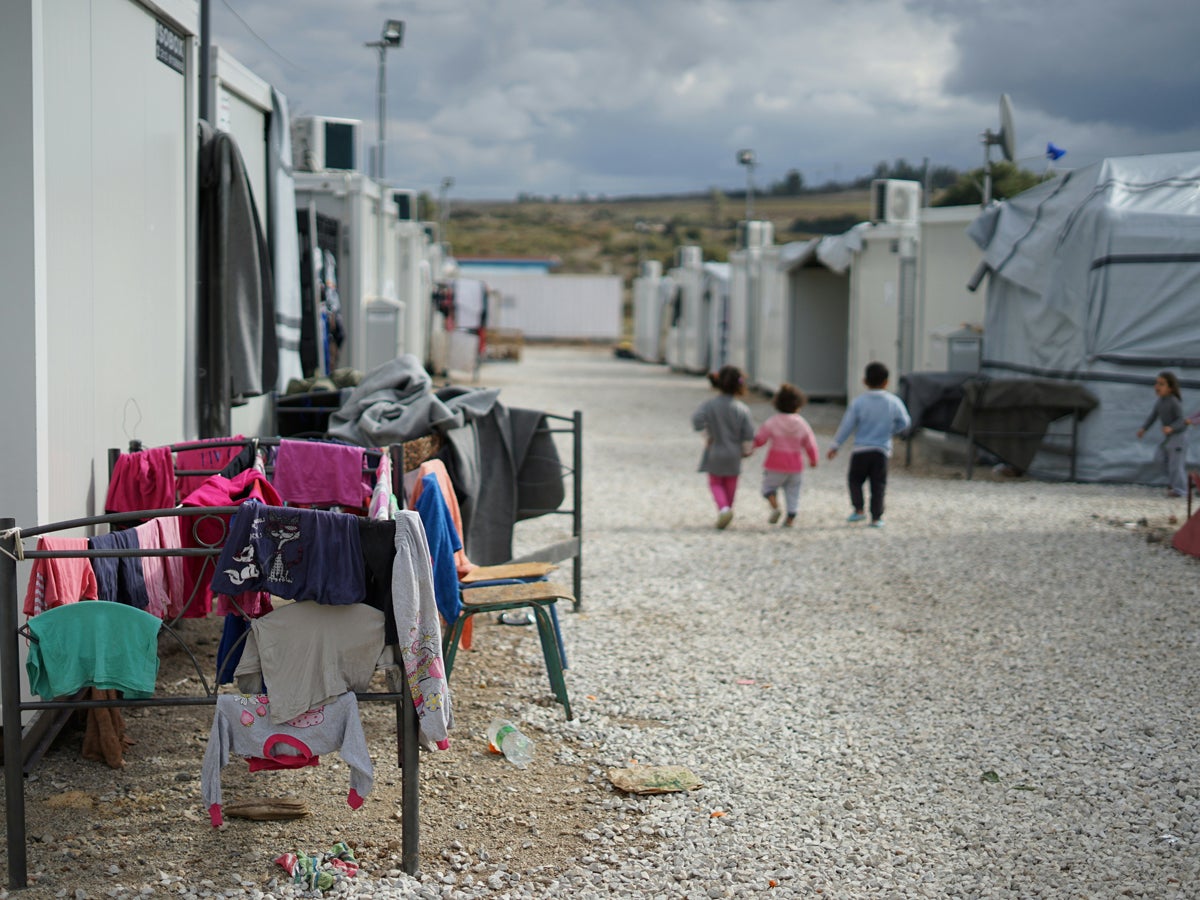 cloudy day, camp site, three children walking, holding hands. Clothes handing on chairs.