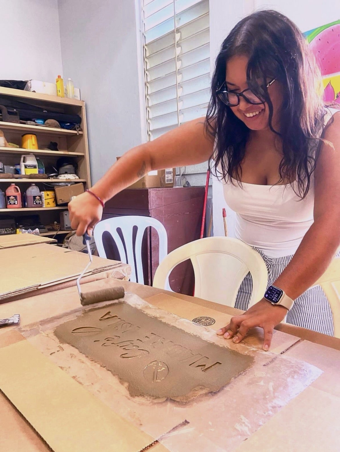 Putzulu uses a stencil to paint the label "Café Madre Isla" for packaging Casa Pueblo's coffee orders.