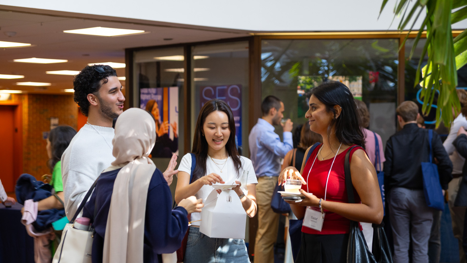 A diverse group of students chatting and smiling while eating snacks at graduate orientation.