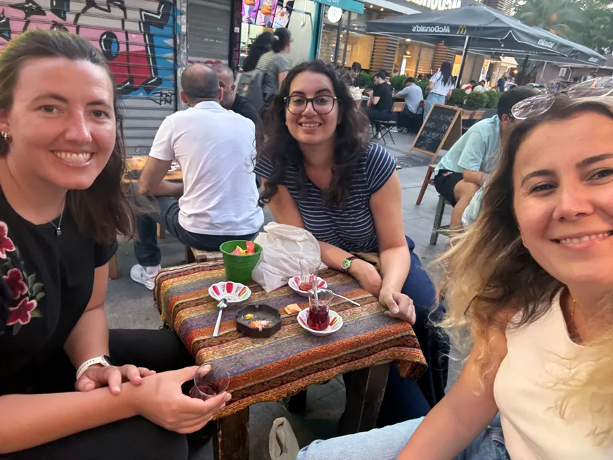 Three female students sitting around a small square table having tea