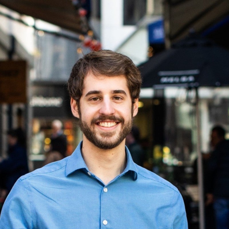 Coby Joseph smiling for a headshot, wearing a blue button down shirt