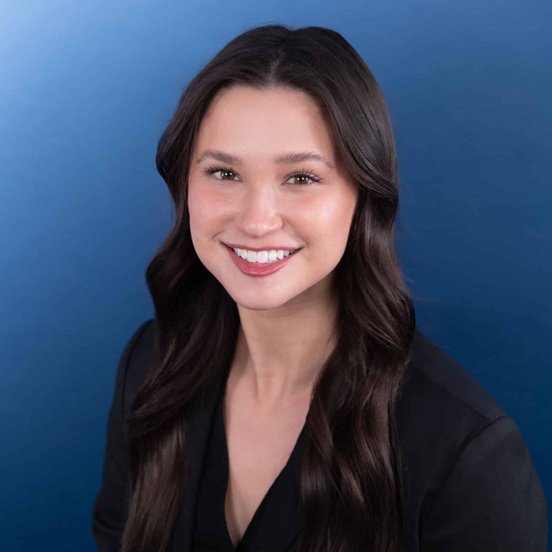 Johanna Yang smiling for a headshot, with a blue backdrop