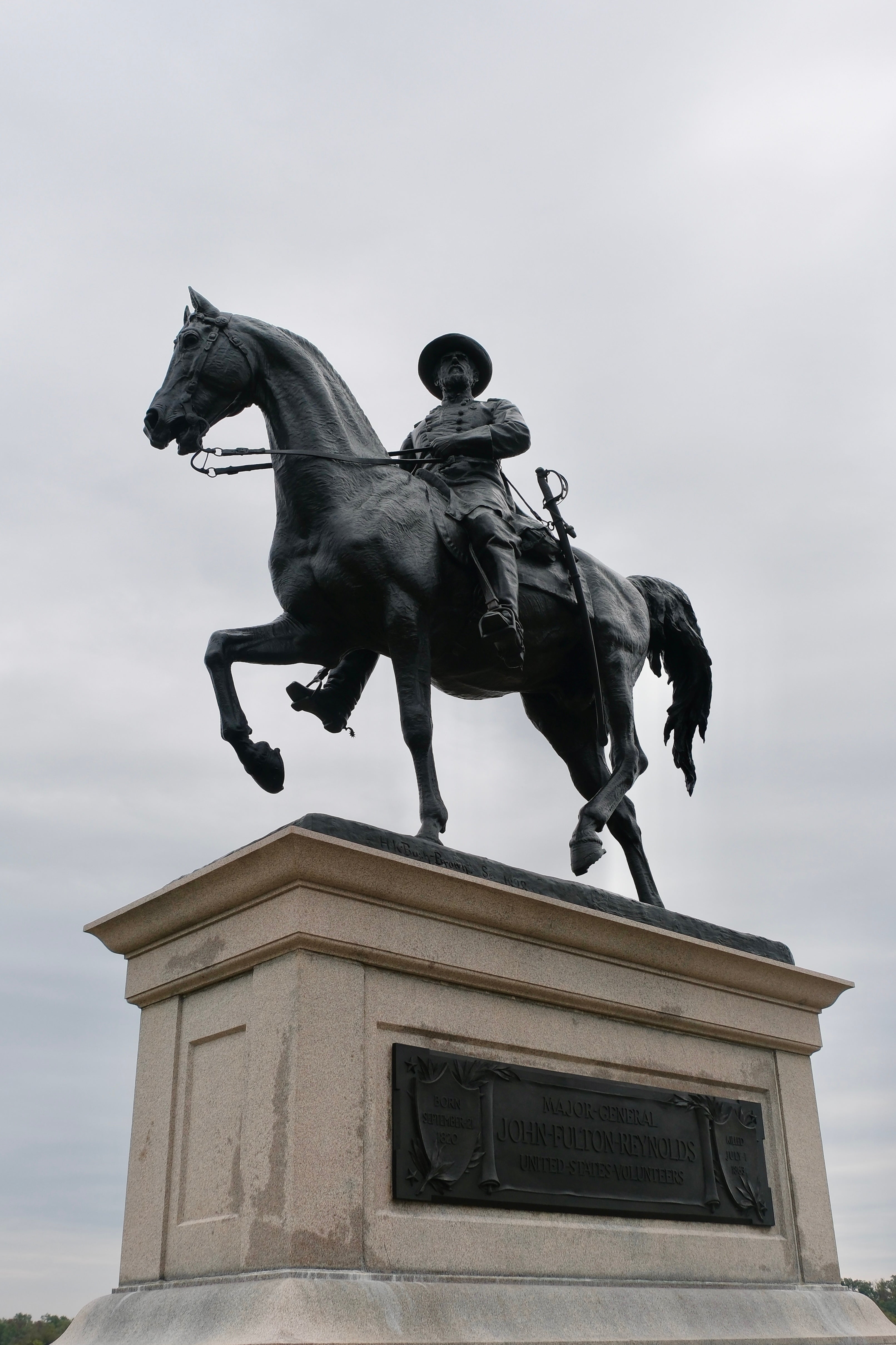 An iron statue of Major-General John Fulton Reynolds atop a stone casket, showing the major riding into battle.