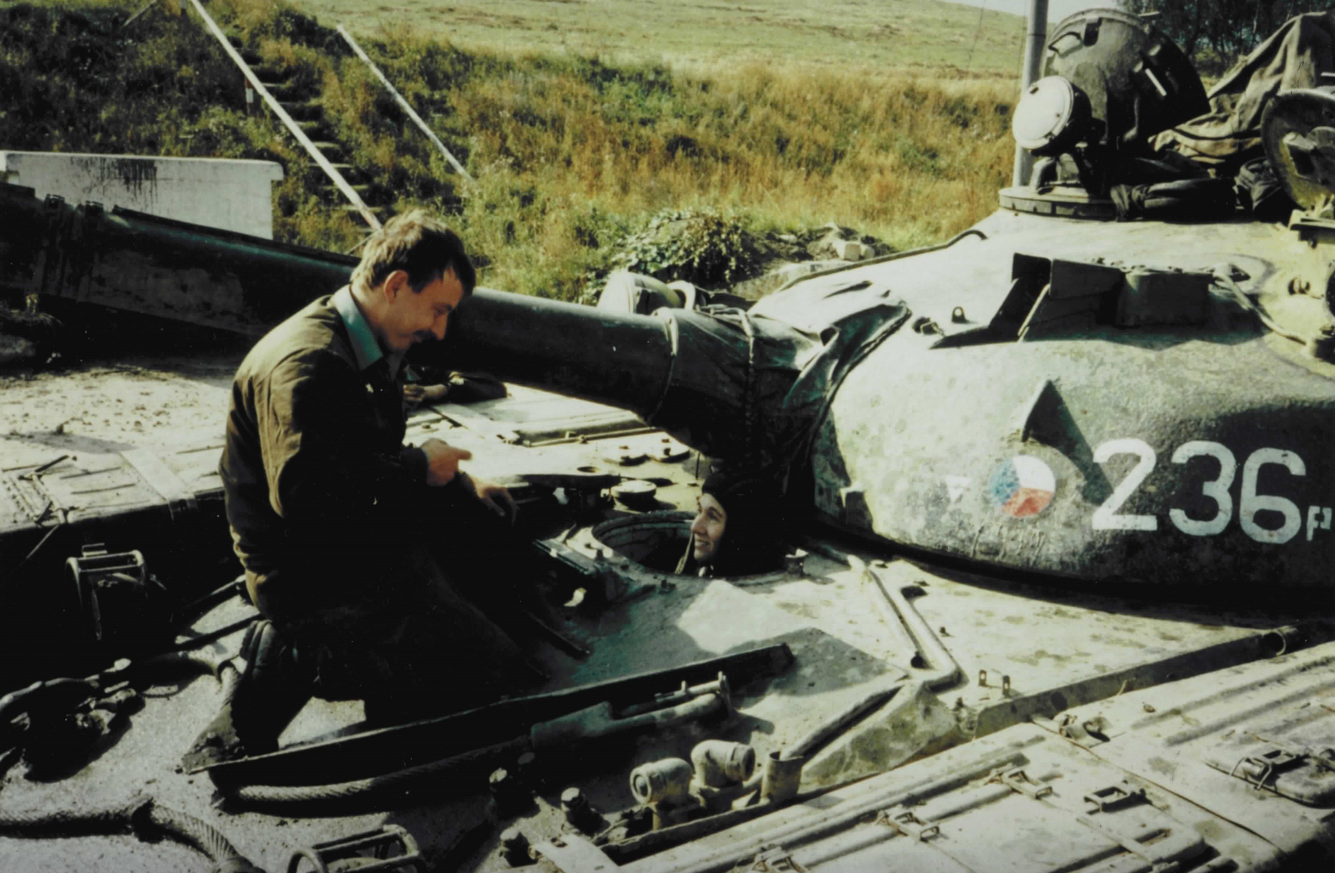Person performing maintenance on a military tank marked with the number 236.