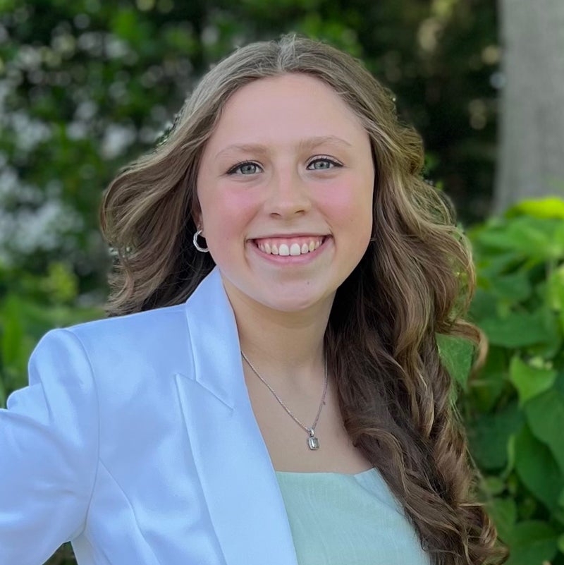Headshot of Ella O'CONNOR smiling, behind her green plants