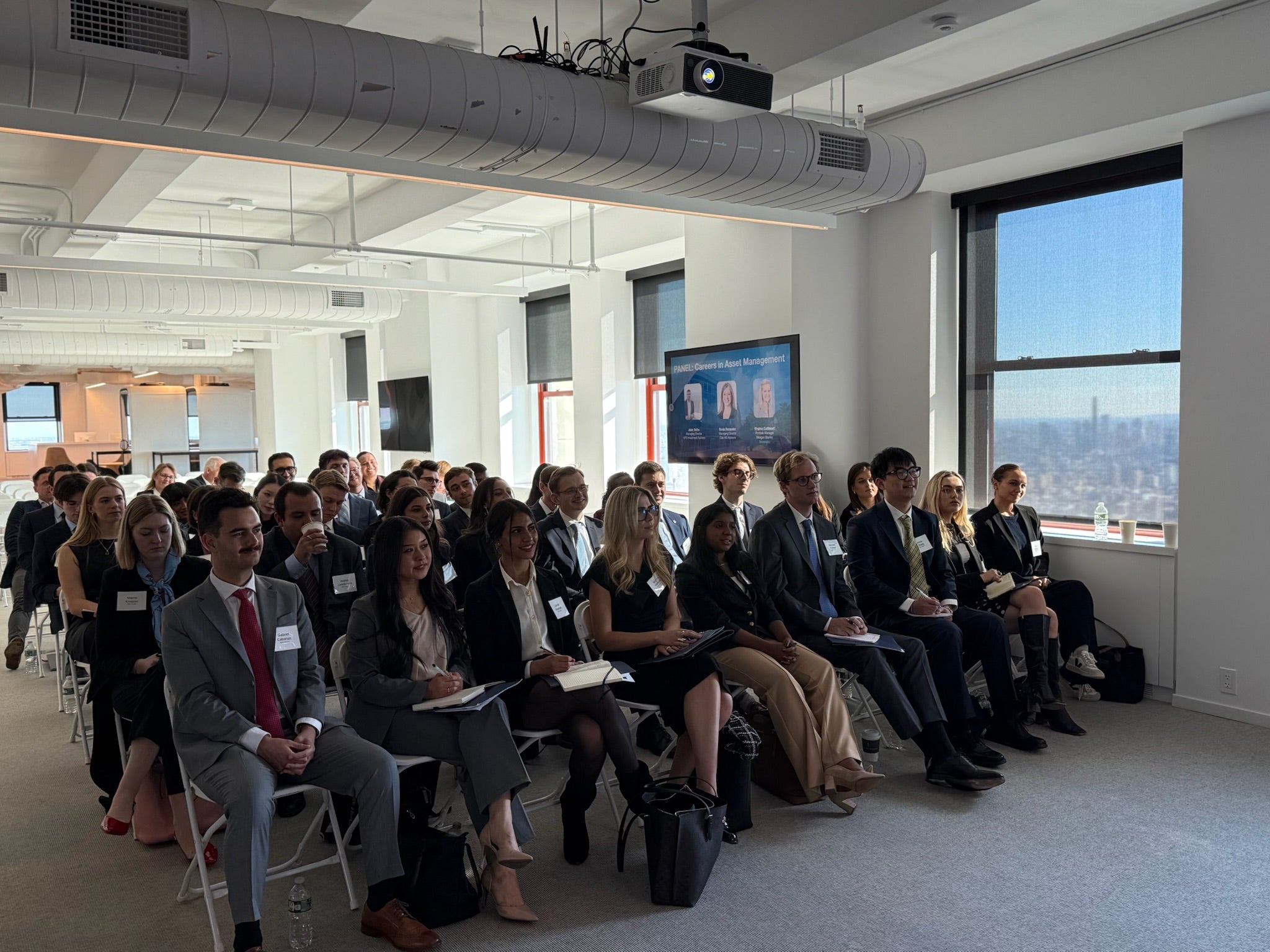 Audience of MSFS students listening to a talk, while taking noted in their notebooks. 