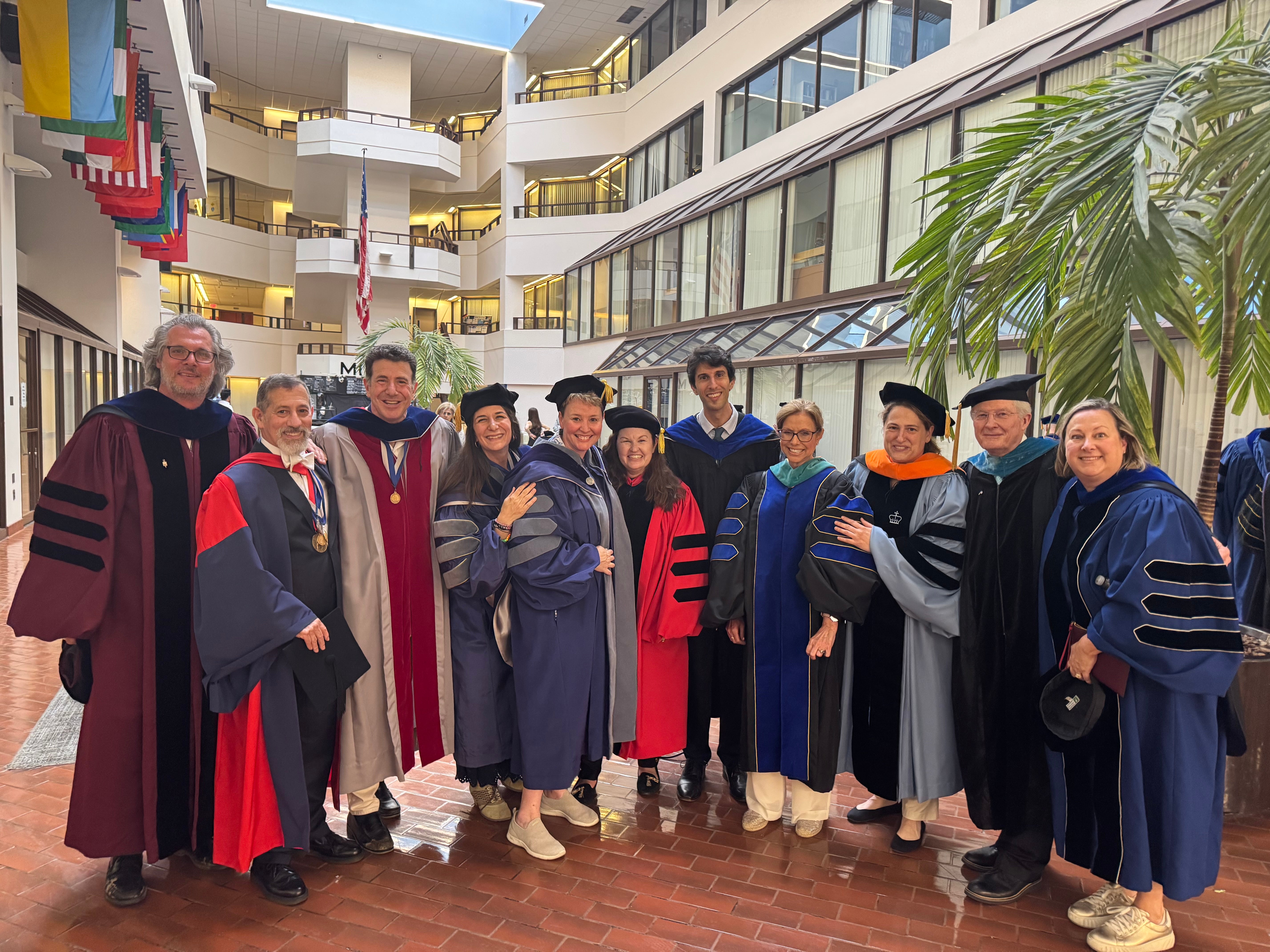 Group of academic faculty in traditional regalia posing together at a university event.