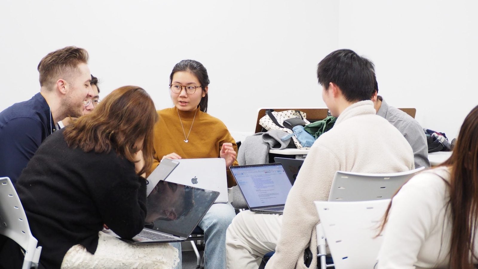 Four students working together, looking at computers while sitting around a table