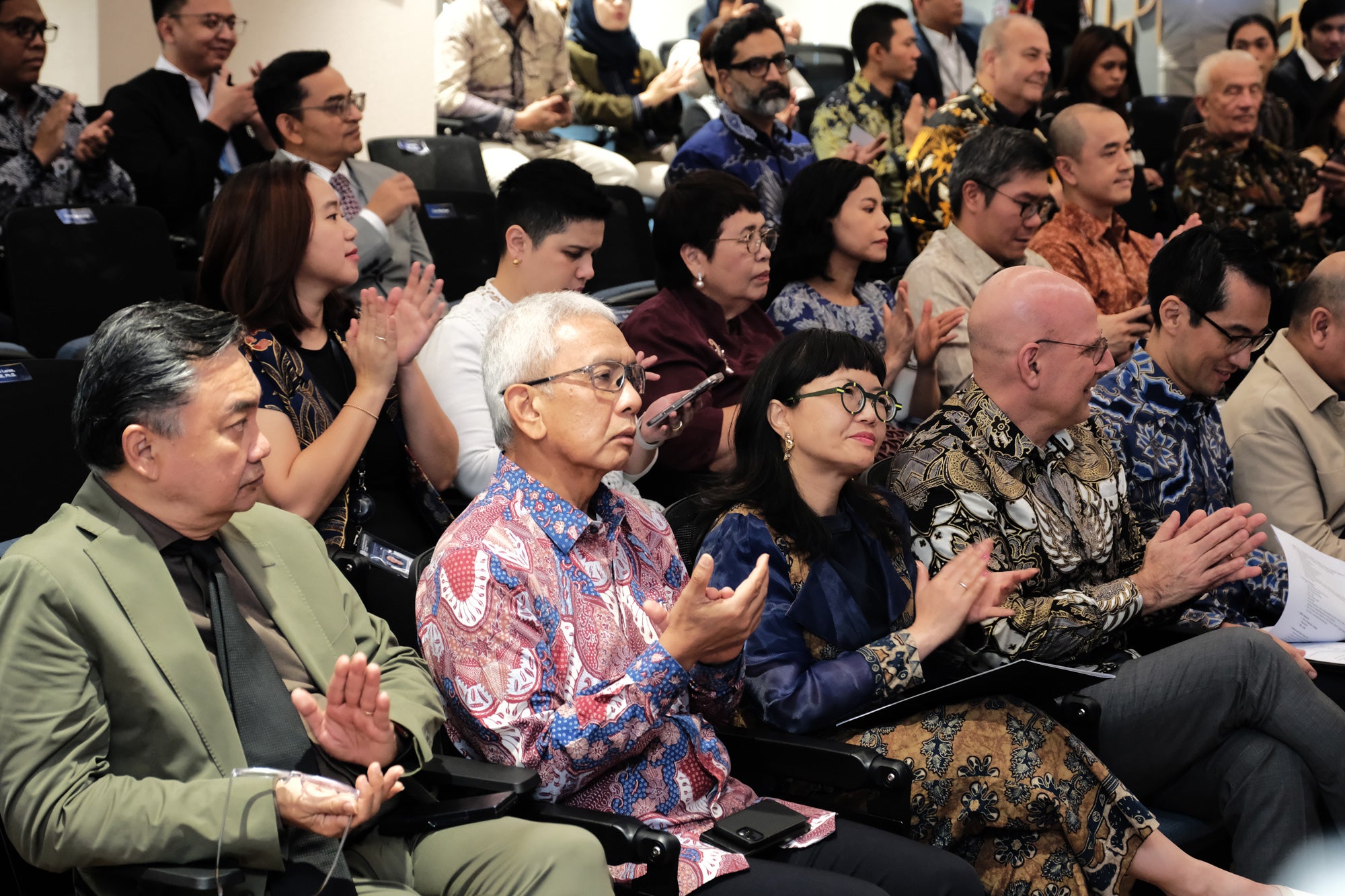 A room filled with audience members clapping