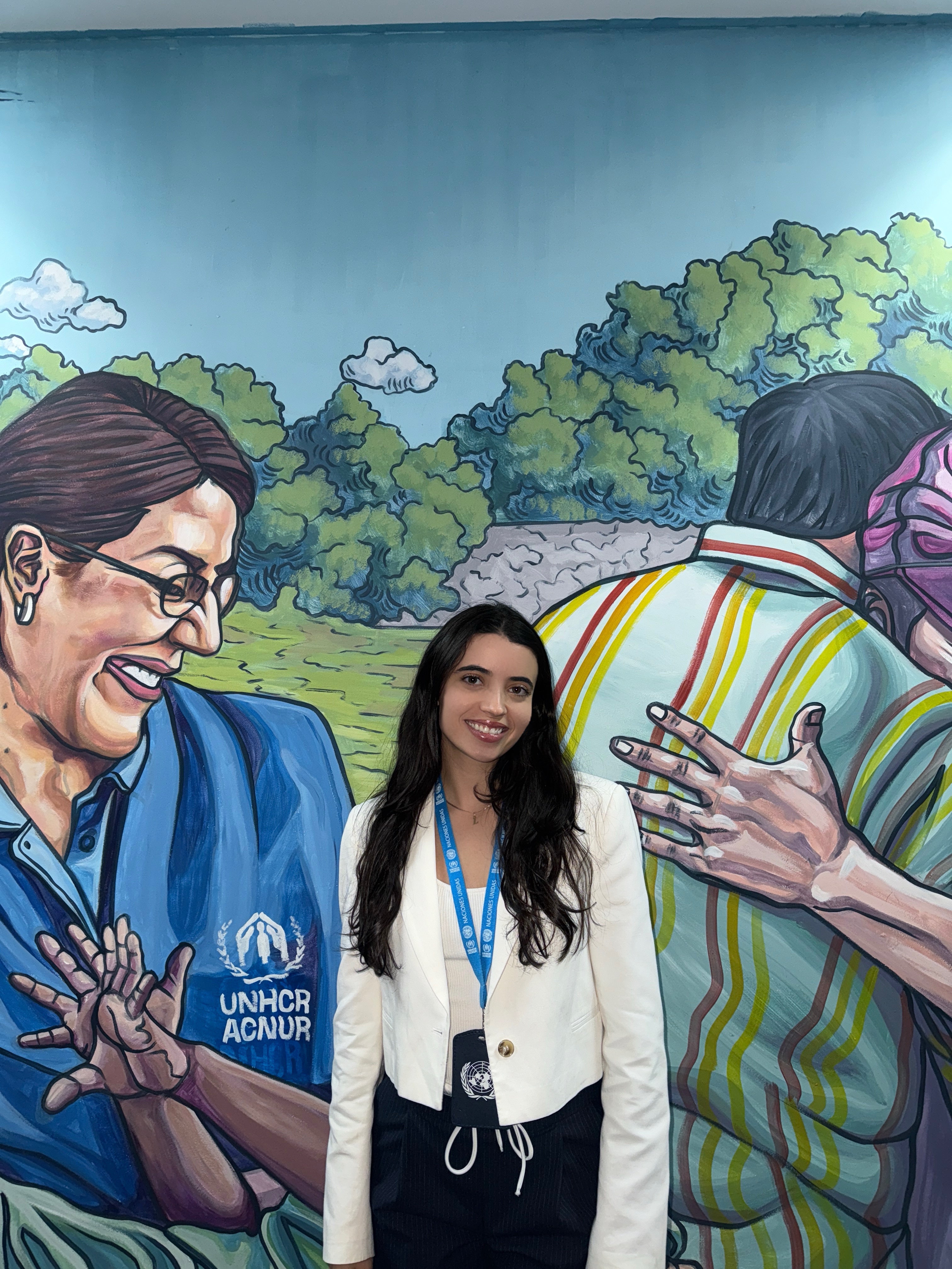 Dahdah poses for a photo with a mural at the The Office of the United Nations High Commissioner for Refugees in Mexico City