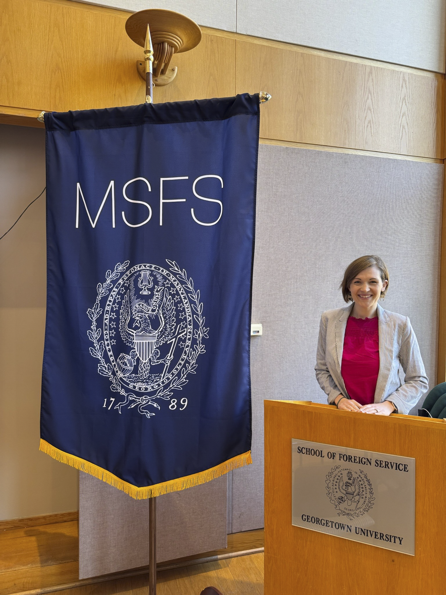 Person standing beside a podium with the Georgetown University School of Foreign Service logo, under a banner reading "MSFS" featuring the university seal.