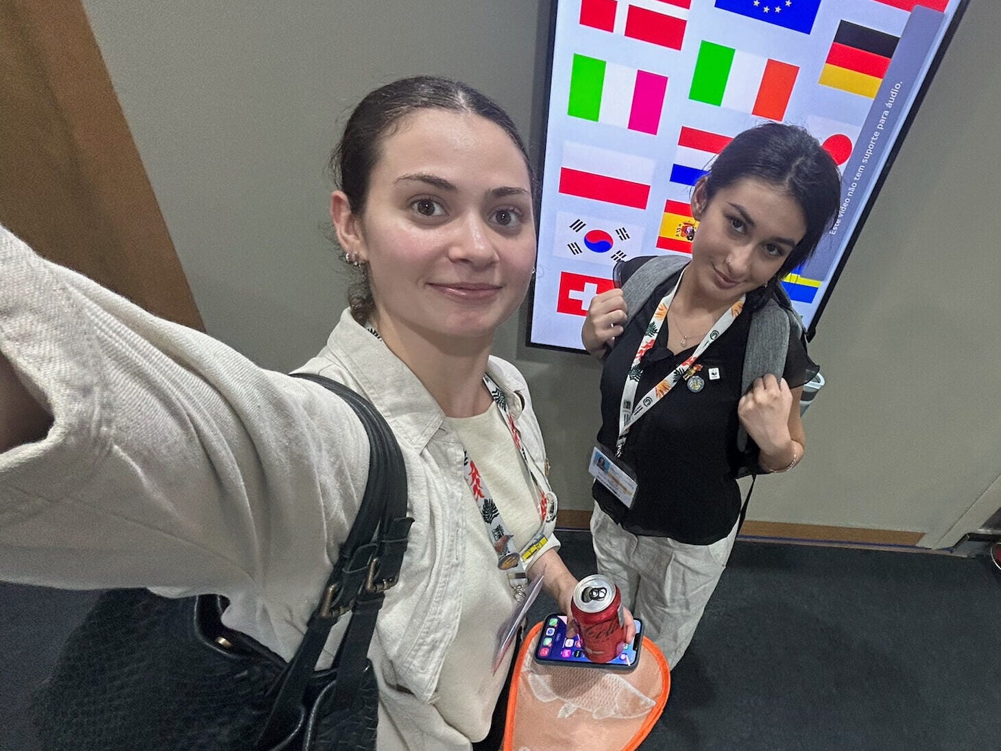 Selfie of Manon Fuchs and Amineh Najam in front of a screen with flags of the world