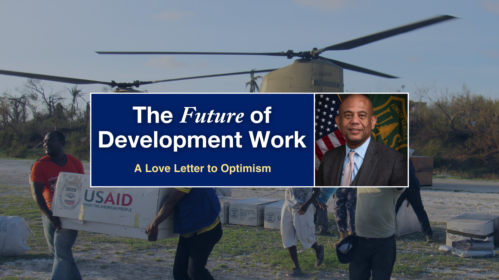 A man in a dark grey suit and pink tie superimposed over an image of people carrying boxes labeled "USAID."