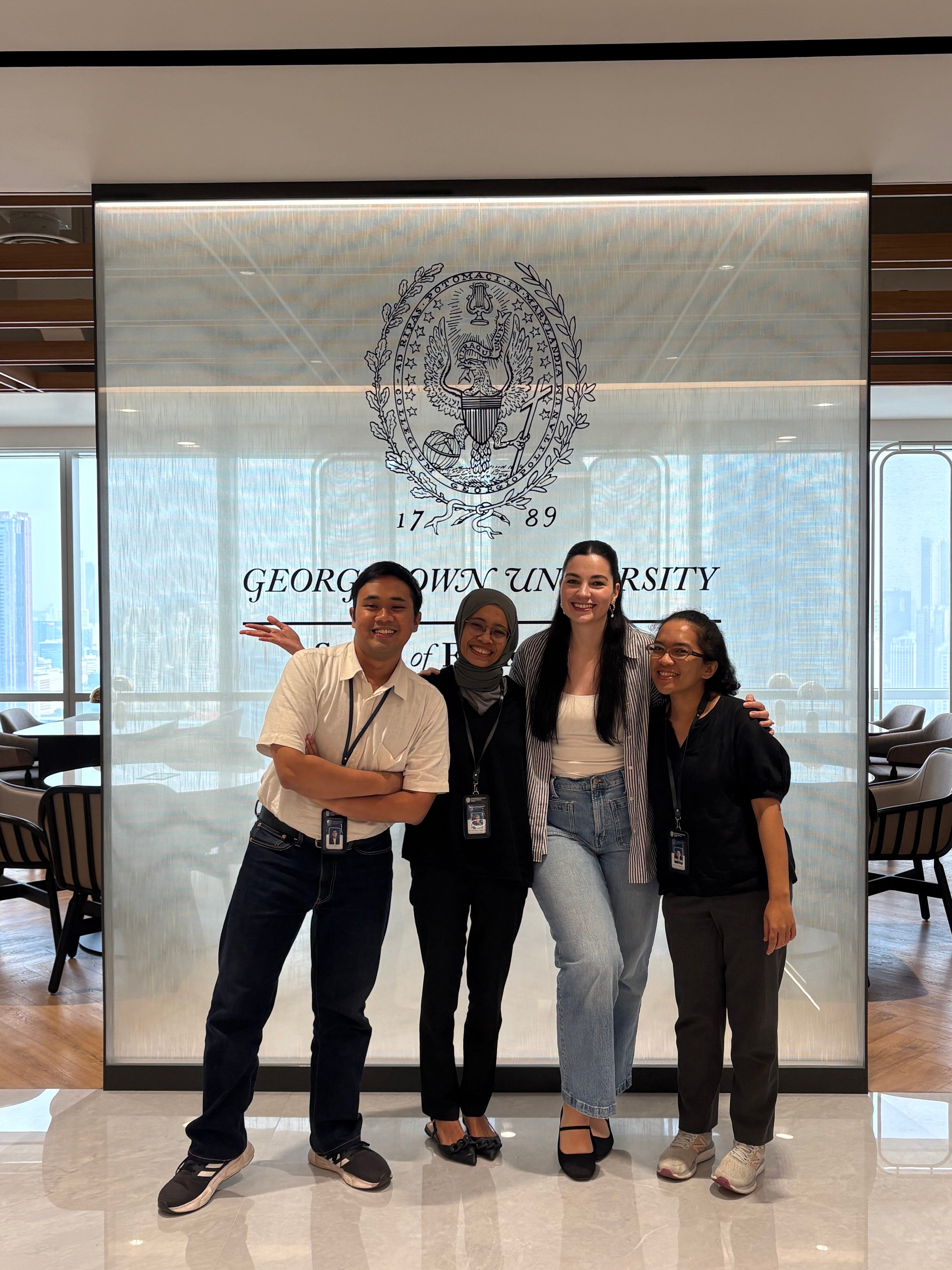 Four people smiling and standing in front of a Georgetown University Asia Pacific logo.