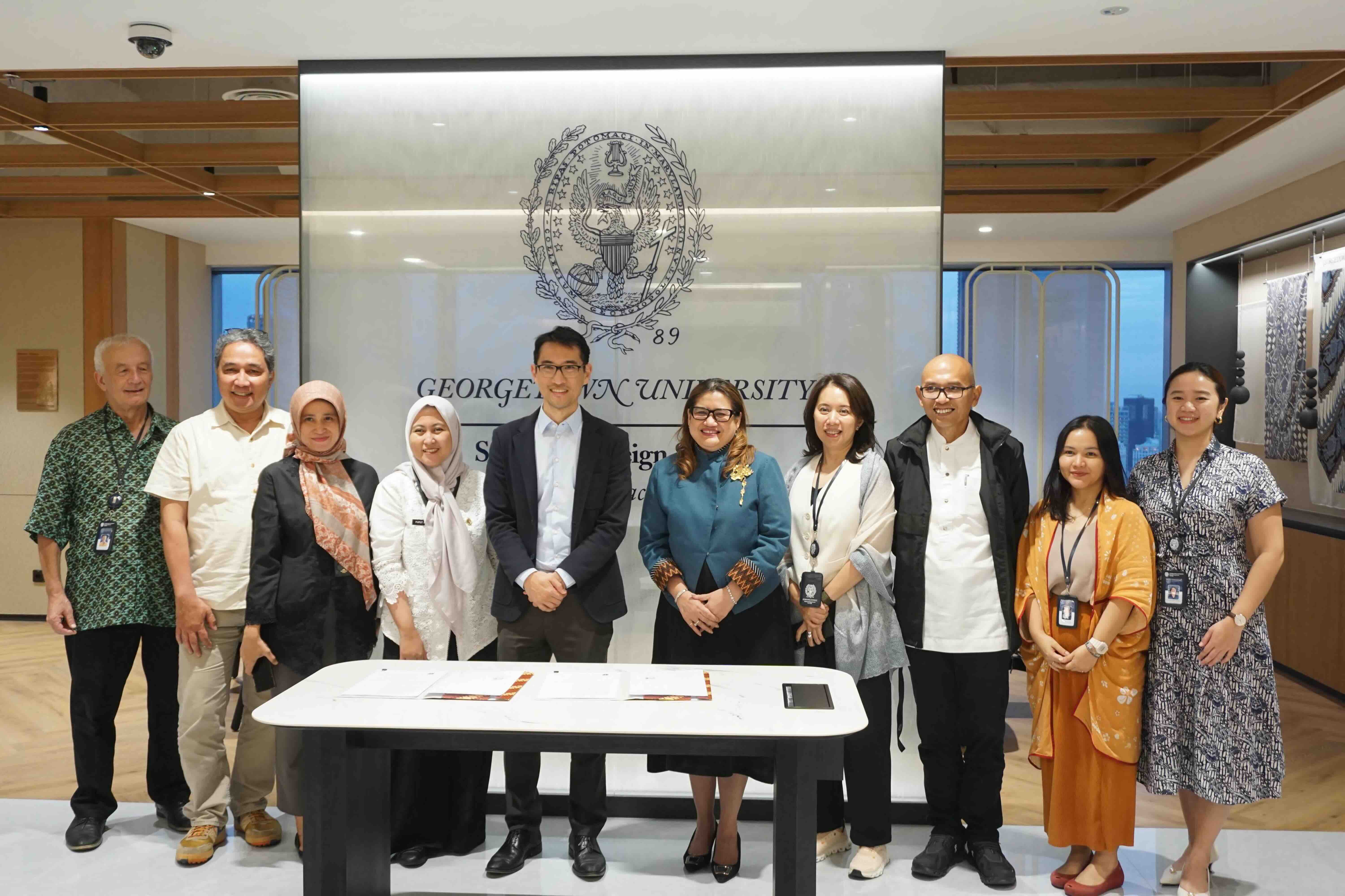 A group of representatives from Bappeda DKI Jakarta and Georgetown SFS Asia Pacific standing in front of a Georgetown backdrop