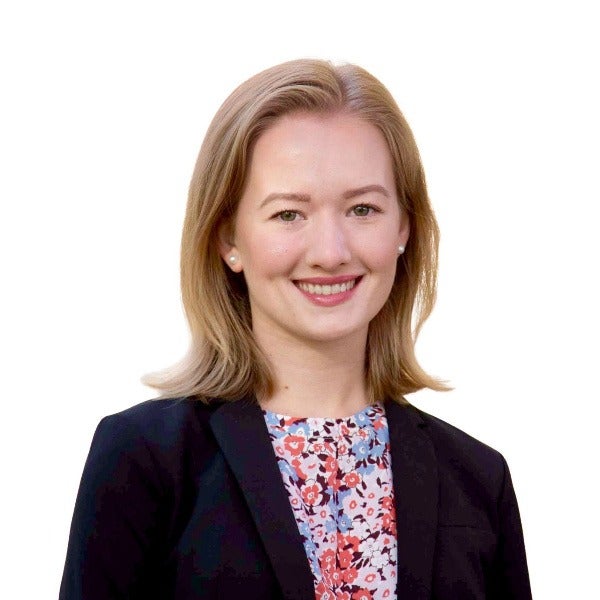 Abbie Treff, shoulder-length blonde hair, warm smile, dark blazer over floral top, white background