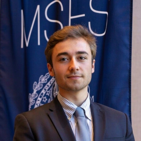 Alexander Dragone, short dark hair, friendly smile, blue textured blazer, patterned tie, yellow pocket square, lapel pin