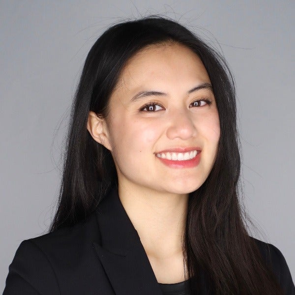 Caitlynn Rais, long dark hair, bright smile, black blazer, gray background