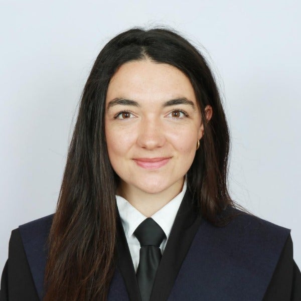 Clementine Gautier, long dark brown hair, light skin tone, gentle smile, navy suit with white shirt and black tie