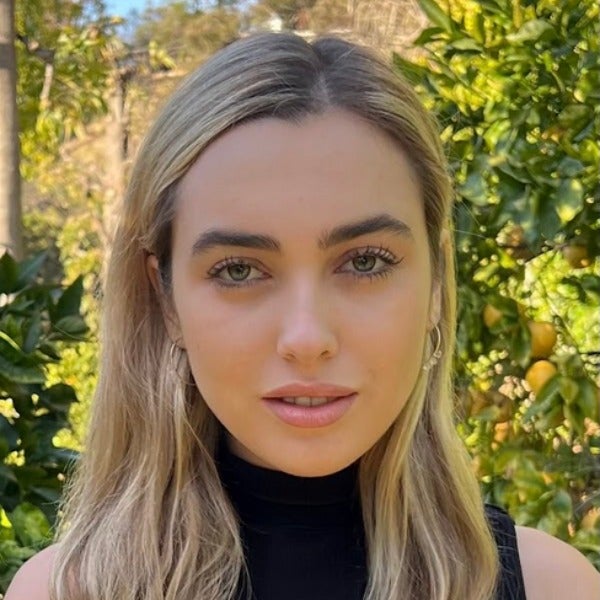 Emily Bass, long blonde hair, natural makeup, black turtleneck, outdoors with citrus trees in background