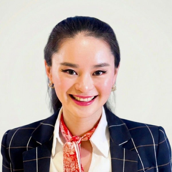 Florence Tang, dark hair pulled back, warm smile, navy windowpane blazer, white shirt, red patterned scarf