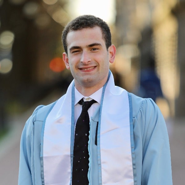 Jack Engel, short dark hair, warm smile, light blue graduation gown, black tie, white shirt