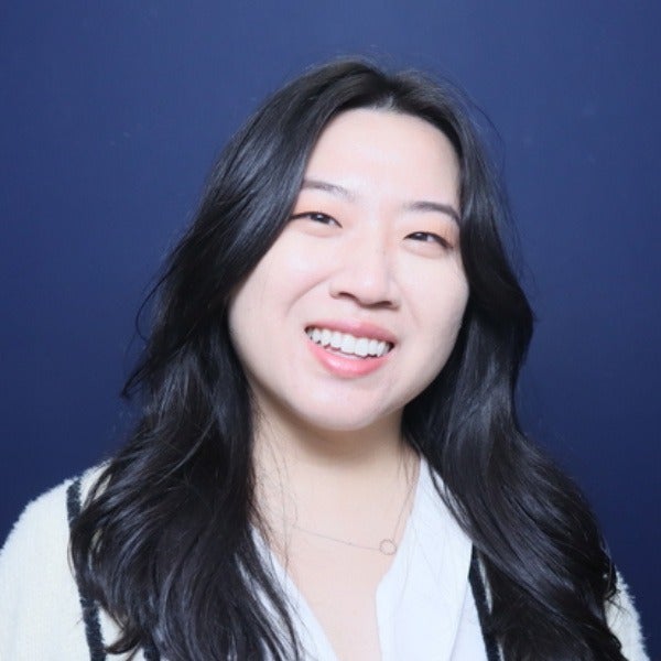 Julie Choi, long black hair, bright smile, white fuzzy sweater, blue background