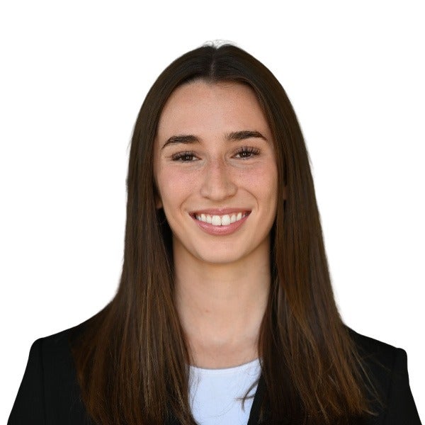 Kalee Dickason, long brown hair, bright smile, black blazer over white top, white background