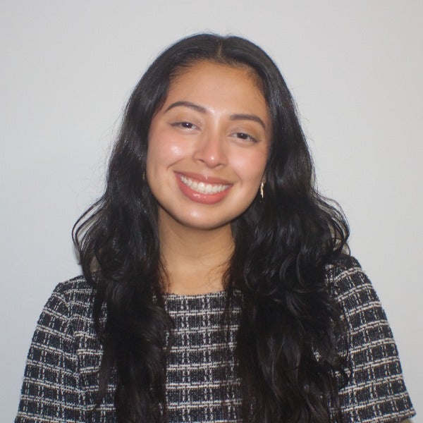 Karen Garcia, long wavy black hair, warm smile, black and white patterned top, light background