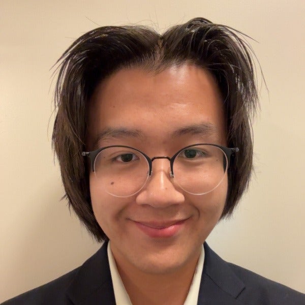 Luke Dao, short dark hair, round glasses, gentle smile, black suit jacket over white shirt