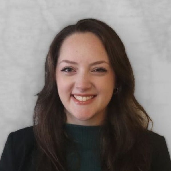 Renee Paul, long blonde hair, warm smile, black blazer, white ribbed top, neutral background