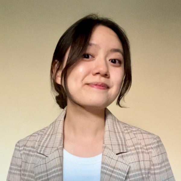 Sarah Lee, dark shoulder-length hair, gentle smile, plaid blazer over white top, beige background