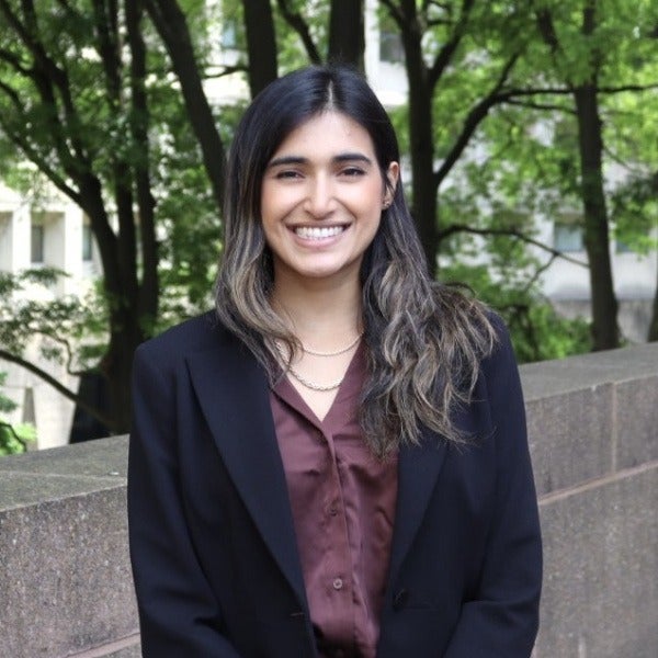 Srishti Banerjee, long dark hair with highlights, warm smile, black blazer over burgundy blouse, layered necklaces