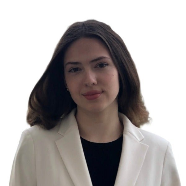 Victoria Kray, shoulder-length dark brown hair, neutral expression, white blazer over black top, light background
