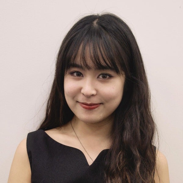 Xinyan Zhang, long dark hair with bangs, warm smile, black sleeveless top, light background