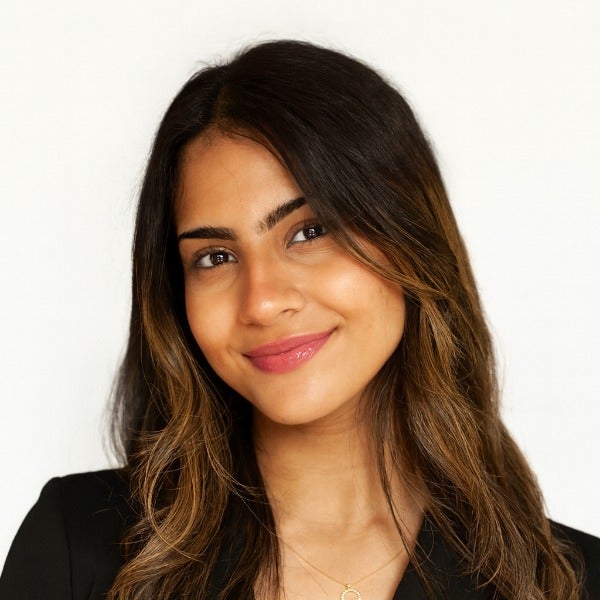 Zeinah Abdelsalam, long brown hair with highlights, warm smile, black blazer, delicate necklace