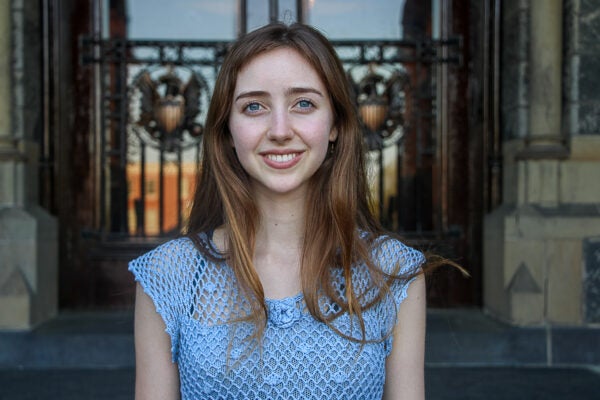 A person with long brown hair wearing a blue crochet top.