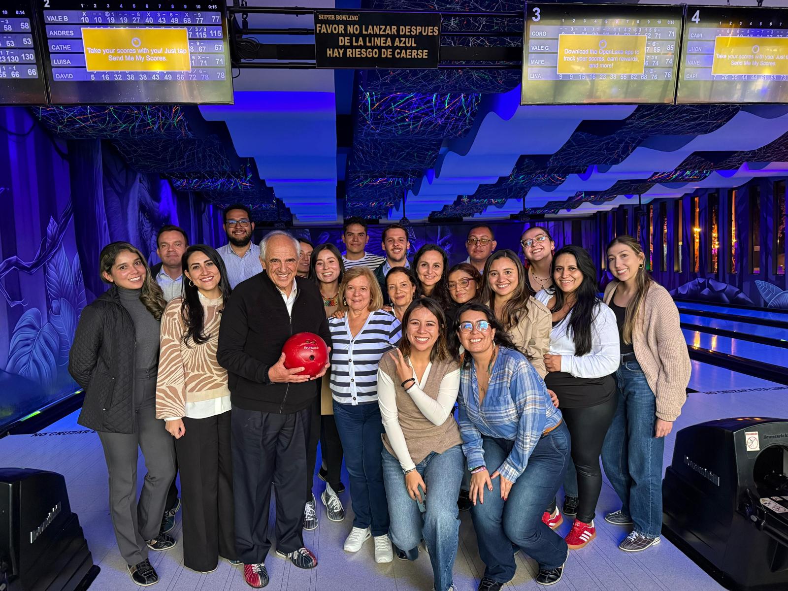 A group of 20 people posing for a photo at a bowling alley.