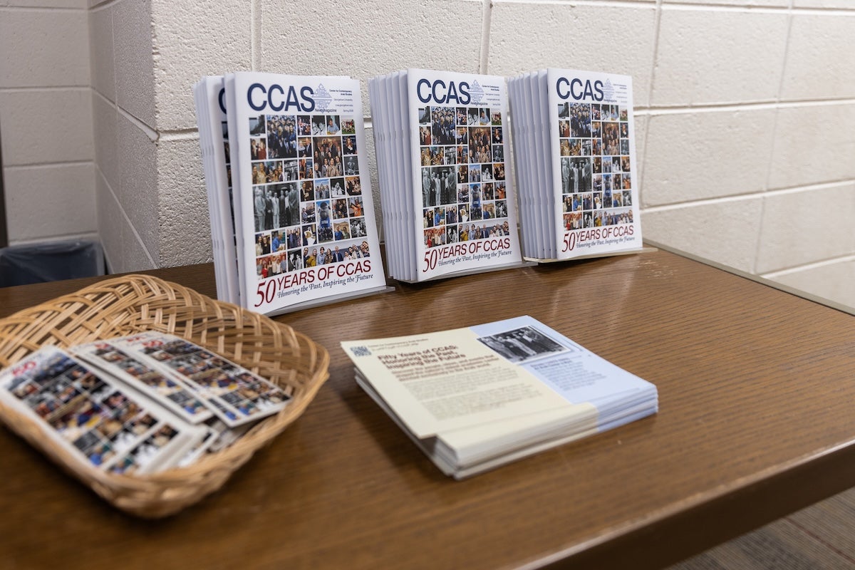 Three columns of the CCAS magazine sit on a table with a stack of brochures. The cover of the magazine says, "50 years of CCAS."