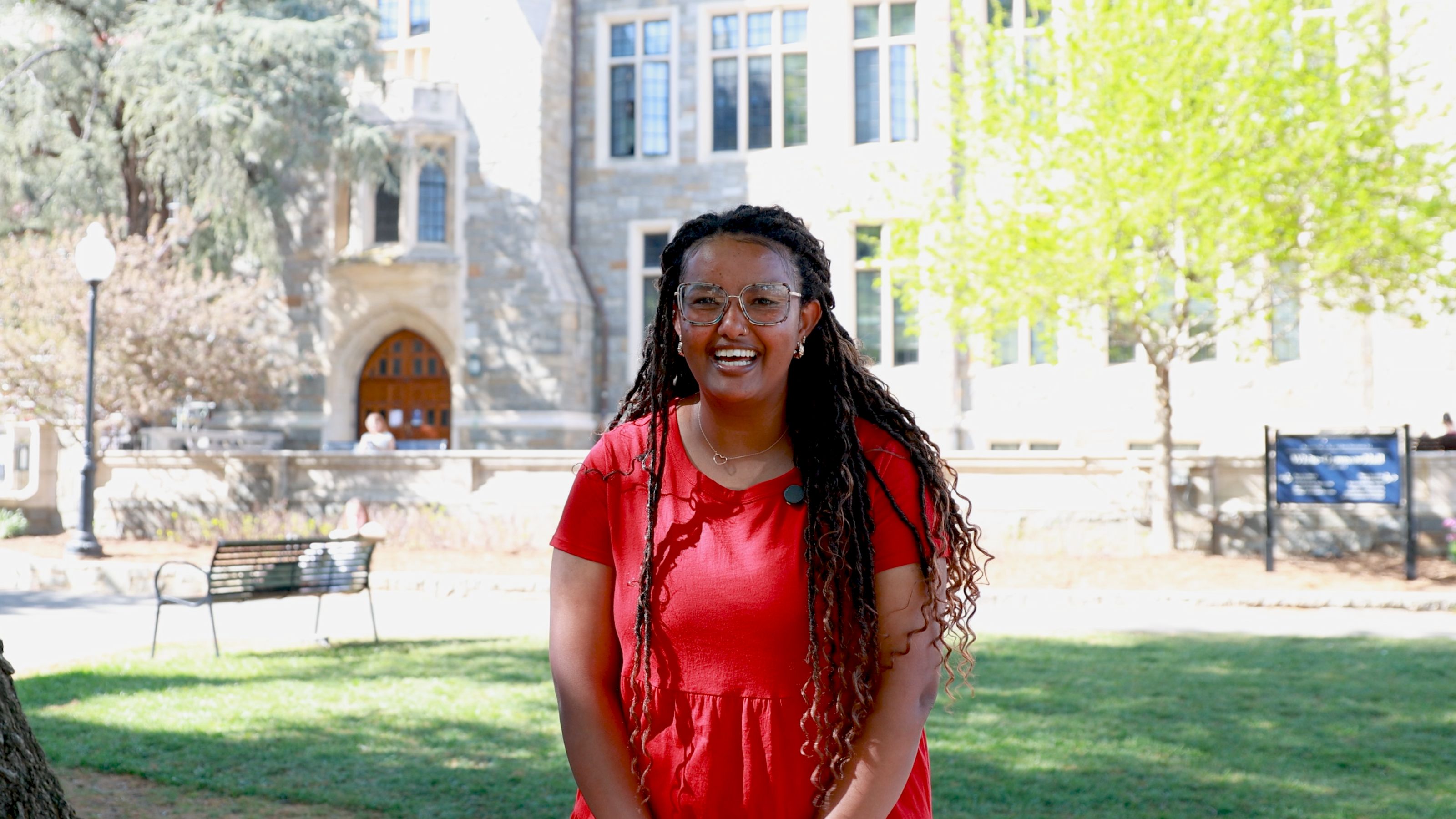 Eyerusalem Cheney smiling in a red dress outside in the grass.