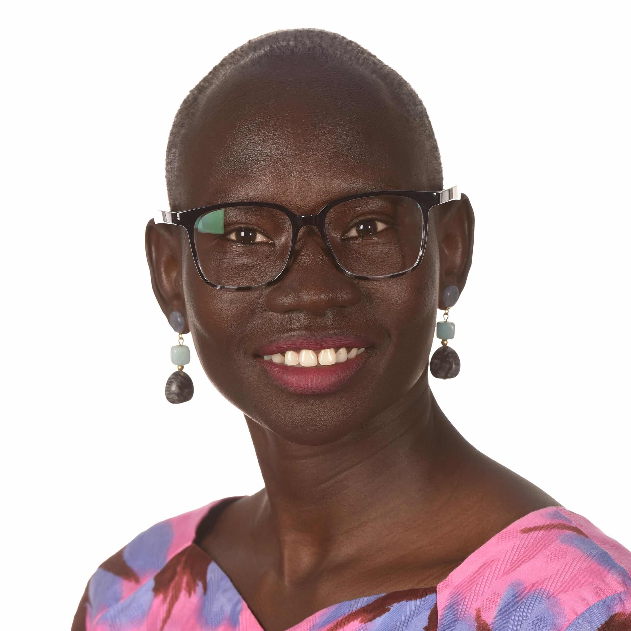 A woman wearing glasses and a pink blouse.