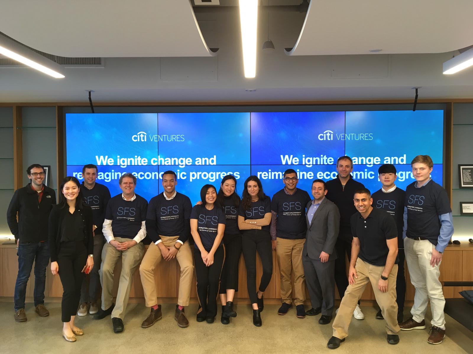 Group of people posed in front of a large set of screens.